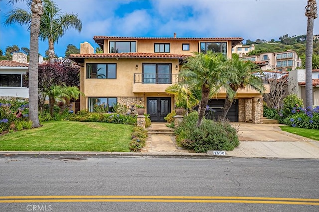 mediterranean / spanish-style house featuring a front yard, a garage, french doors, and a balcony