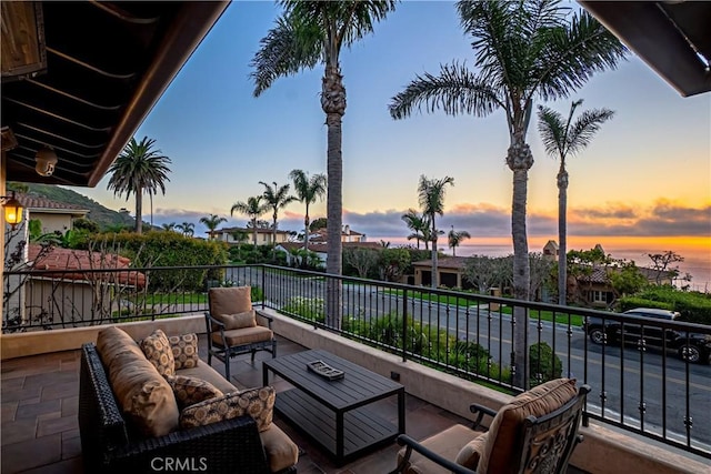 patio terrace at dusk featuring an outdoor hangout area and a balcony