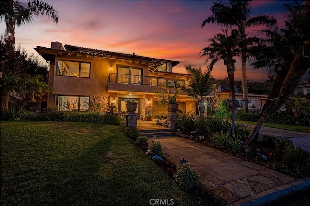 view of front of home featuring a yard and a balcony