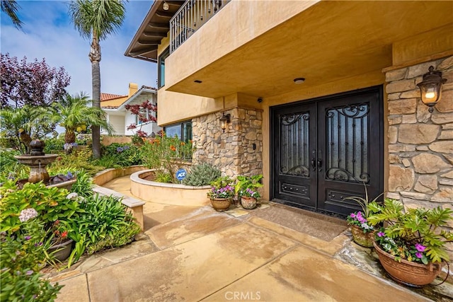 view of exterior entry with a balcony and french doors