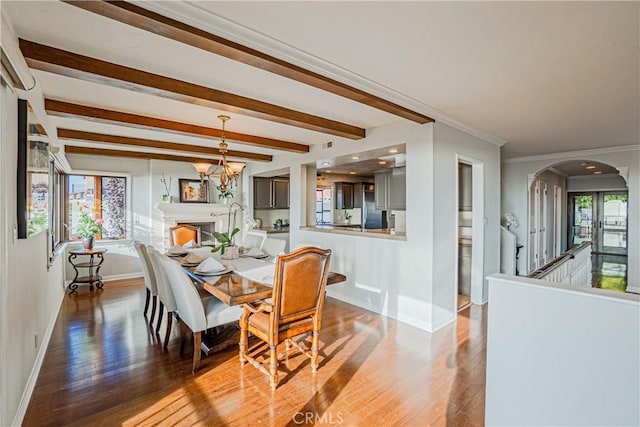 dining area with wood-type flooring, beamed ceiling, crown molding, and a chandelier