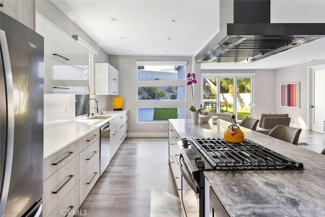 kitchen with extractor fan, sink, white cabinets, light stone counters, and stainless steel appliances