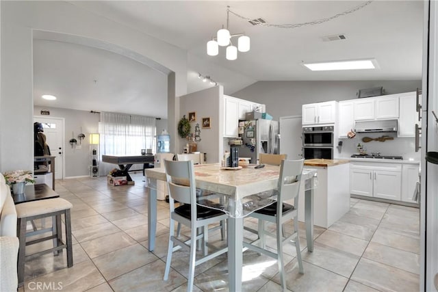 kitchen with white cabinetry, butcher block counters, appliances with stainless steel finishes, range hood, and vaulted ceiling