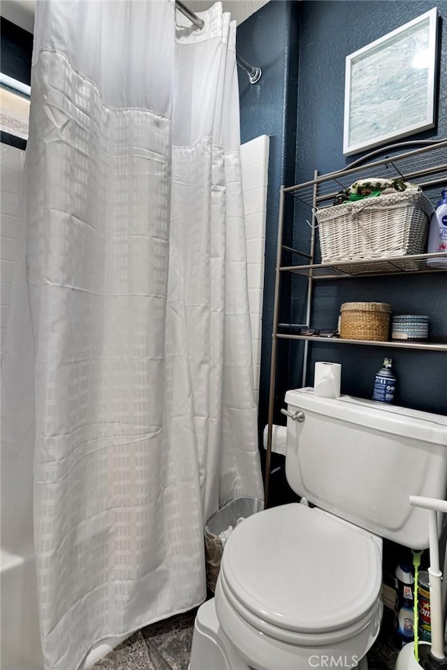 bathroom featuring toilet and shower / bath combination with curtain