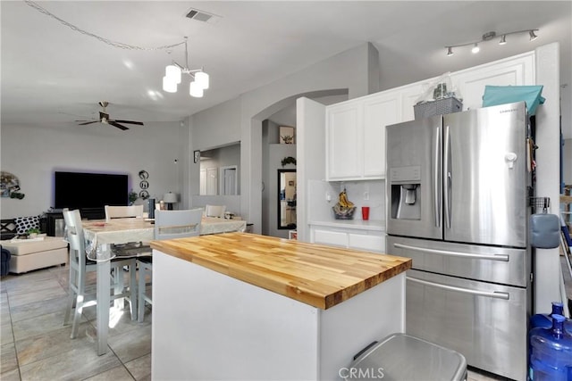 kitchen with wooden counters, pendant lighting, white cabinetry, stainless steel fridge with ice dispenser, and ceiling fan with notable chandelier