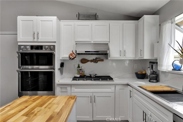 kitchen with white cabinetry, appliances with stainless steel finishes, lofted ceiling, and extractor fan