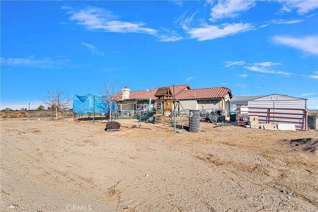 back of house featuring a trampoline and a playground