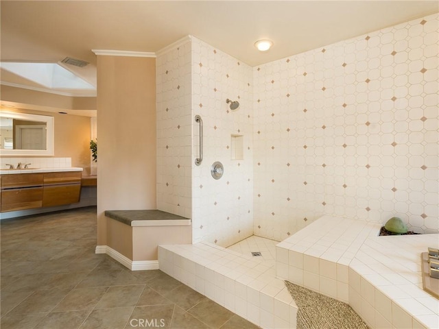 bathroom featuring vanity, tile patterned floors, crown molding, a skylight, and a tile shower