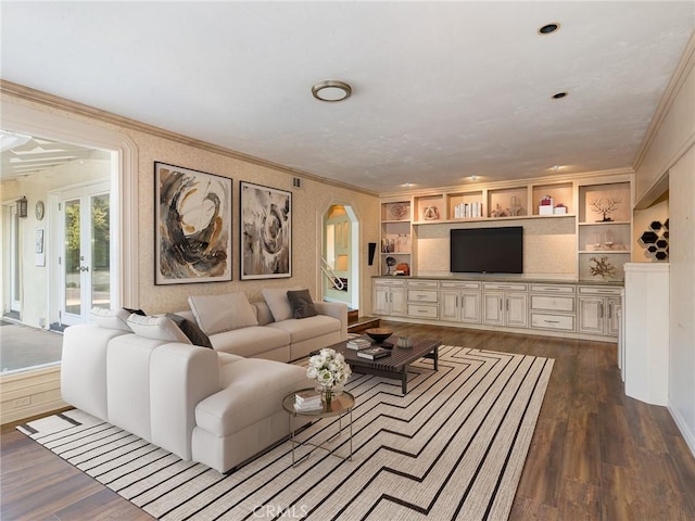 living room featuring built in shelves, dark hardwood / wood-style flooring, and crown molding