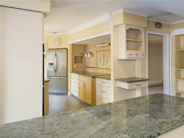 kitchen with stainless steel refrigerator with ice dispenser, ornamental molding, and dark stone counters