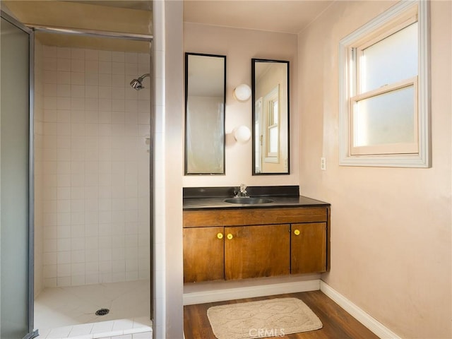 bathroom featuring hardwood / wood-style flooring, a shower with shower door, and vanity