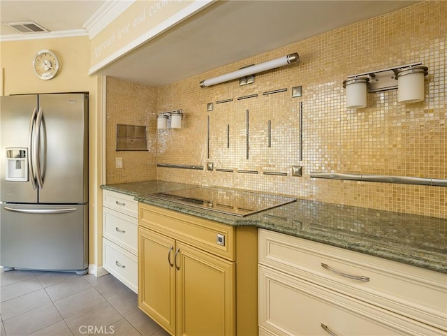 kitchen featuring backsplash, dark stone counters, ornamental molding, electric stovetop, and stainless steel fridge