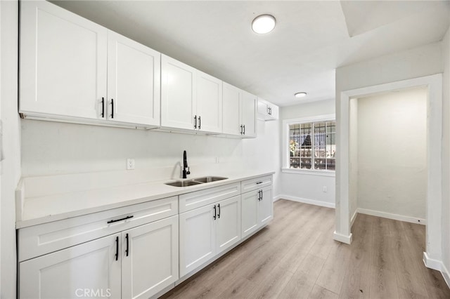 bar with sink, white cabinetry, and light wood-type flooring