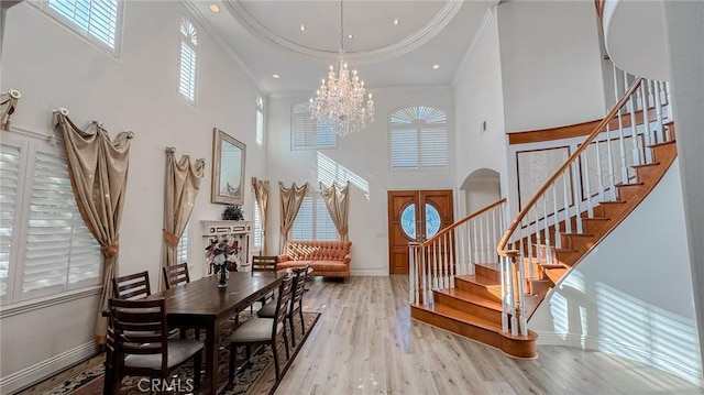 foyer with crown molding, an inviting chandelier, light wood-type flooring, and a high ceiling