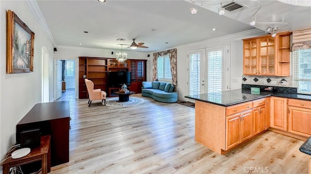 kitchen featuring backsplash, ornamental molding, kitchen peninsula, dark stone counters, and light wood-type flooring