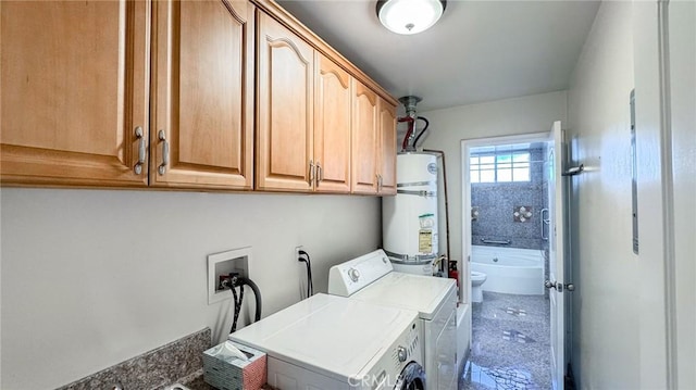 washroom with cabinets, washing machine and clothes dryer, and water heater