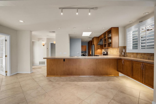 kitchen with tasteful backsplash, kitchen peninsula, a skylight, and stainless steel appliances