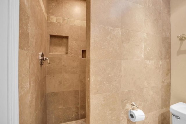 bathroom featuring toilet and a tile shower