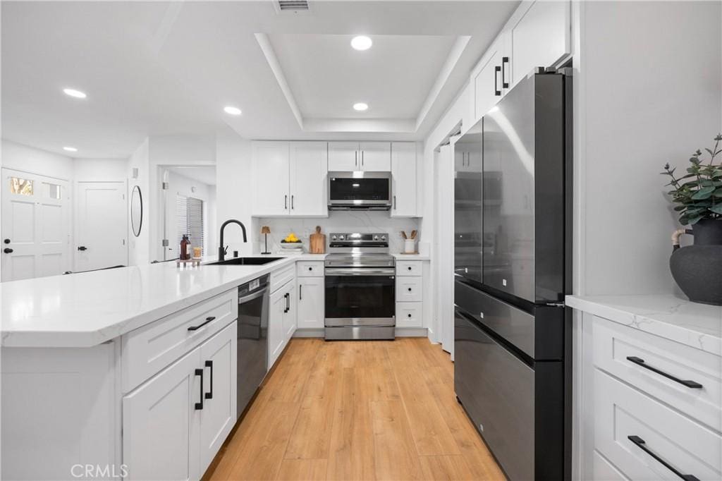 kitchen with appliances with stainless steel finishes, white cabinets, and sink