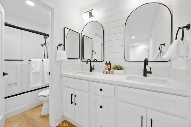 full bathroom with toilet, hardwood / wood-style flooring, enclosed tub / shower combo, and vanity