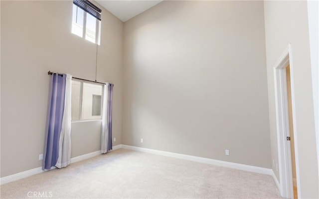 carpeted spare room with a towering ceiling