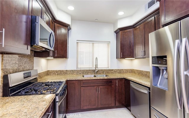 kitchen with sink, light stone counters, and stainless steel appliances