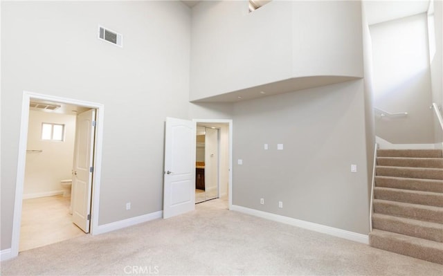 carpeted spare room featuring a high ceiling