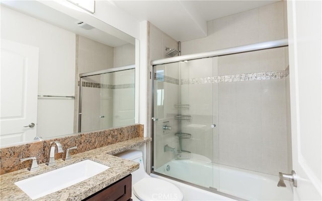 full bathroom with toilet, bath / shower combo with glass door, and vanity