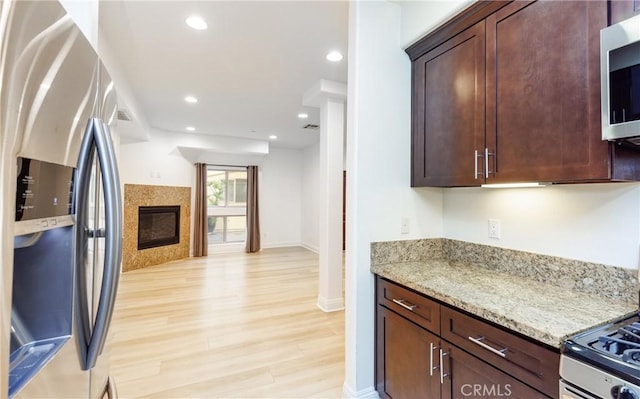 kitchen with appliances with stainless steel finishes, light stone counters, and light hardwood / wood-style floors