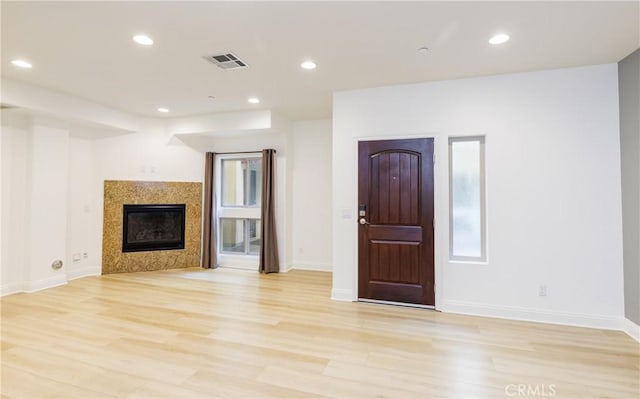 unfurnished living room featuring a tiled fireplace and light hardwood / wood-style floors