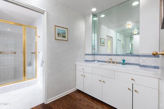 bathroom featuring hardwood / wood-style flooring, an enclosed shower, vanity, and tasteful backsplash