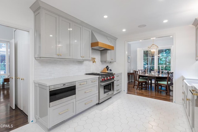 kitchen with high end stainless steel range oven, light tile patterned floors, gray cabinetry, decorative backsplash, and custom range hood