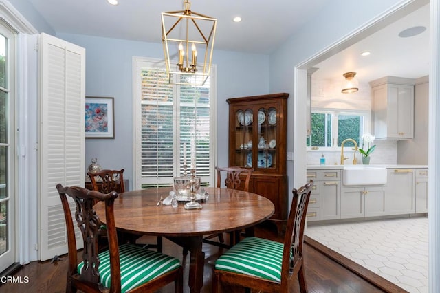 dining area with sink, dark hardwood / wood-style floors, and a notable chandelier