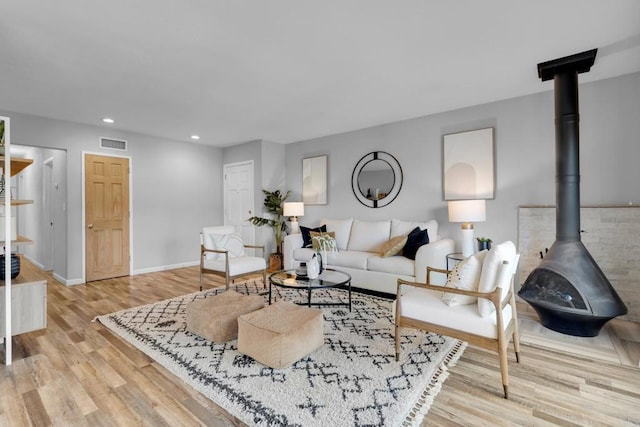 living room with light hardwood / wood-style floors and a wood stove