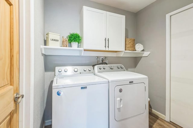 washroom featuring hardwood / wood-style floors, cabinets, and separate washer and dryer