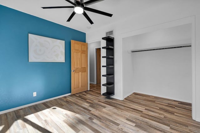 unfurnished bedroom with ceiling fan, wood-type flooring, and a closet