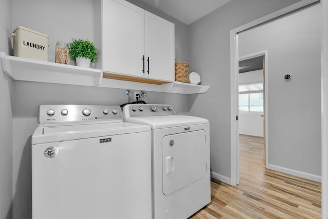 laundry area with separate washer and dryer, cabinets, and light hardwood / wood-style floors