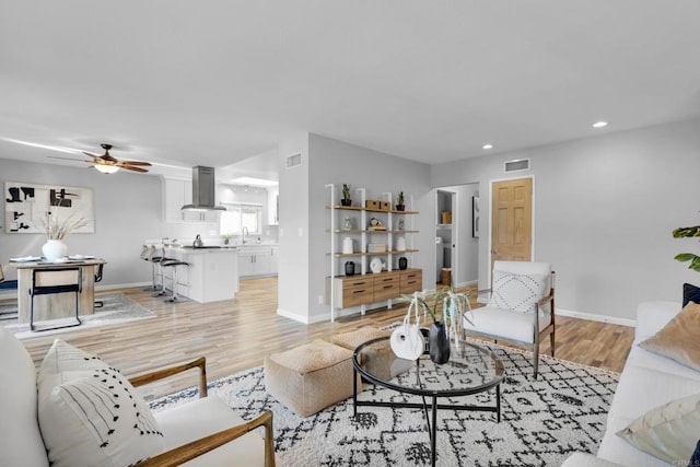 living room featuring light hardwood / wood-style floors, sink, and ceiling fan