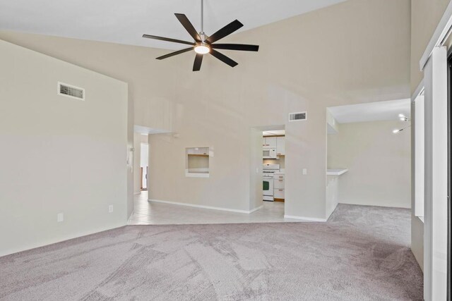 unfurnished living room featuring light carpet, ceiling fan, and high vaulted ceiling