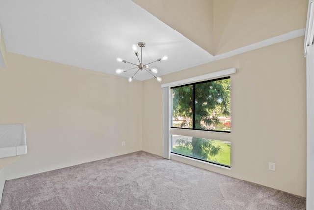 carpeted spare room with a notable chandelier