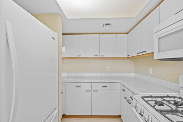 kitchen with white cabinetry, white appliances, and tile counters