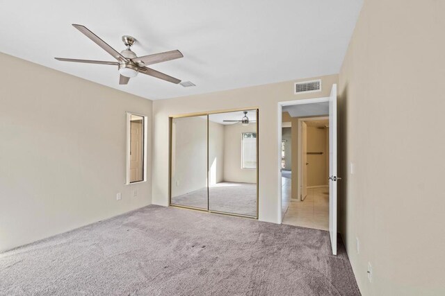 unfurnished bedroom with ceiling fan, a closet, and light carpet