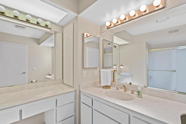 bathroom featuring a shower with door and vanity