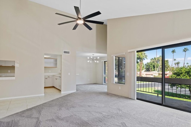 unfurnished living room with light carpet, ceiling fan with notable chandelier, and a towering ceiling