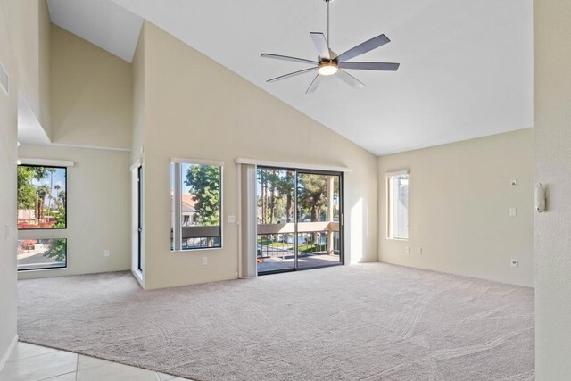 unfurnished living room featuring ceiling fan, light colored carpet, a wealth of natural light, and high vaulted ceiling