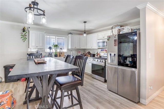 kitchen featuring decorative light fixtures, kitchen peninsula, white cabinetry, ornamental molding, and stainless steel appliances