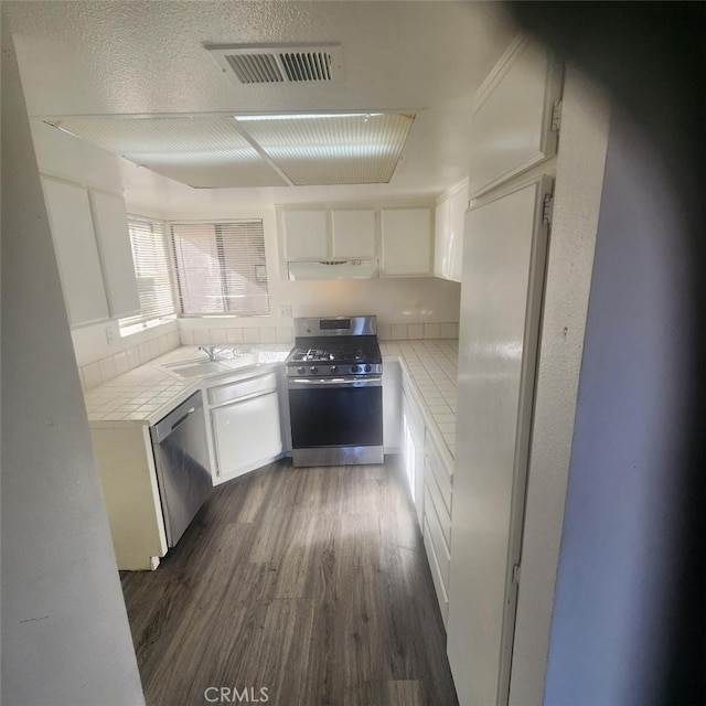 kitchen with sink, appliances with stainless steel finishes, dark hardwood / wood-style flooring, and white cabinetry