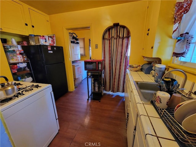 kitchen featuring sink, black appliances, tile countertops, and washer / dryer