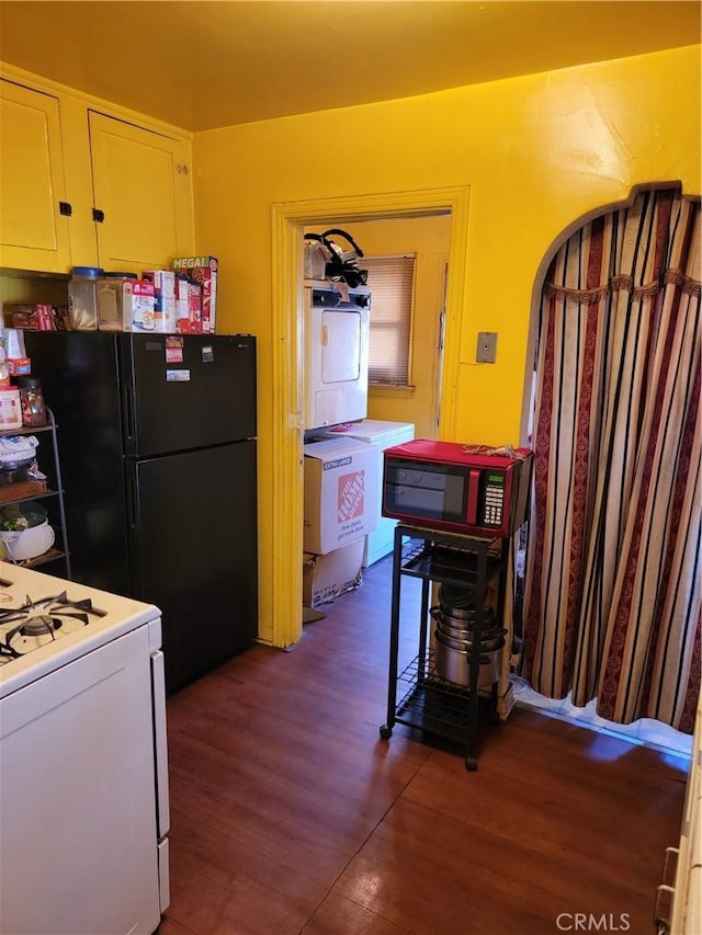 kitchen with white cabinets, black fridge, dark wood-type flooring, and white range oven