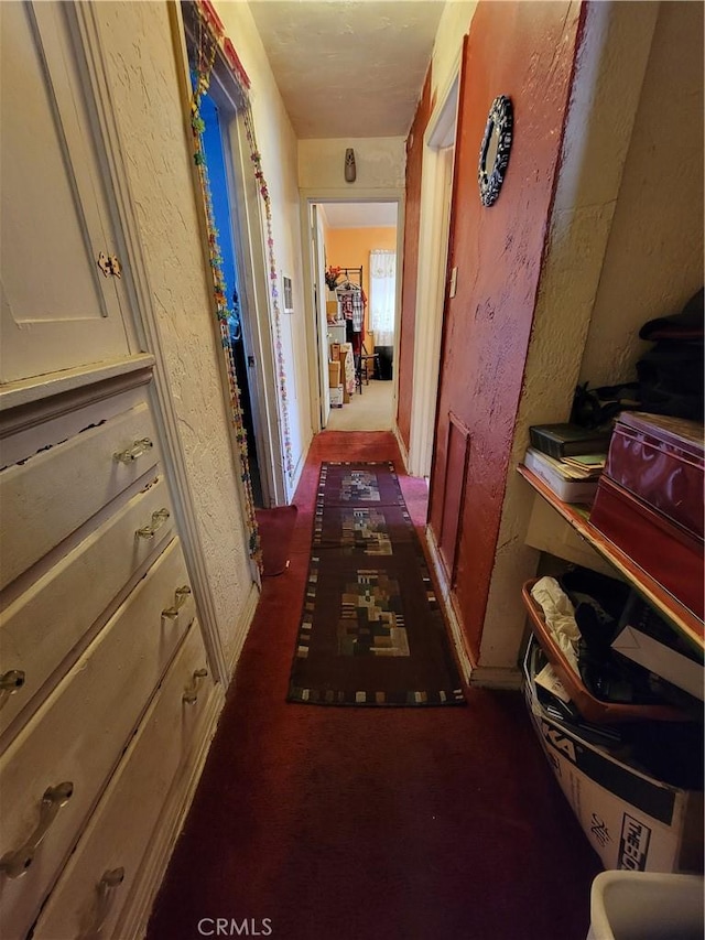 hallway featuring dark colored carpet